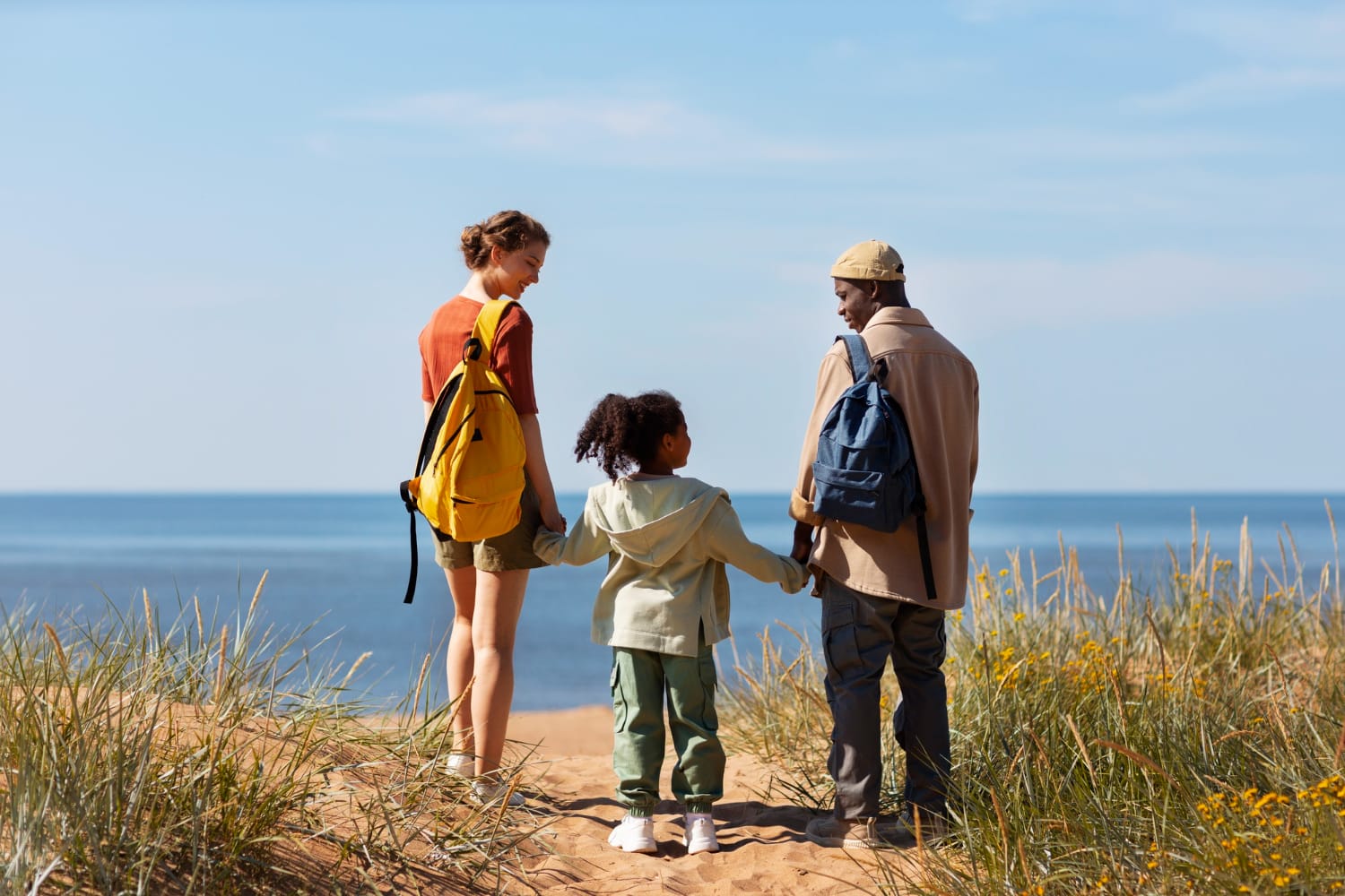 Gezin van drie loopt over het strand en kan op vakantie zonder rugklachten.